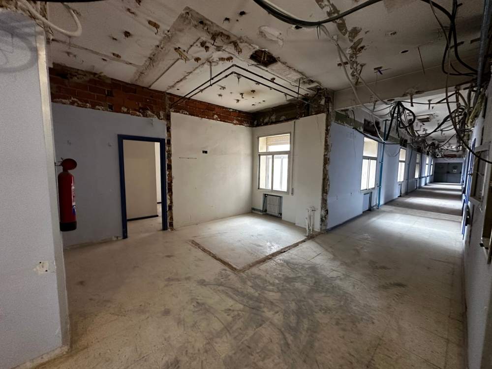 Zona de consultas del hospital con falsos techos retirados y la planta en obra